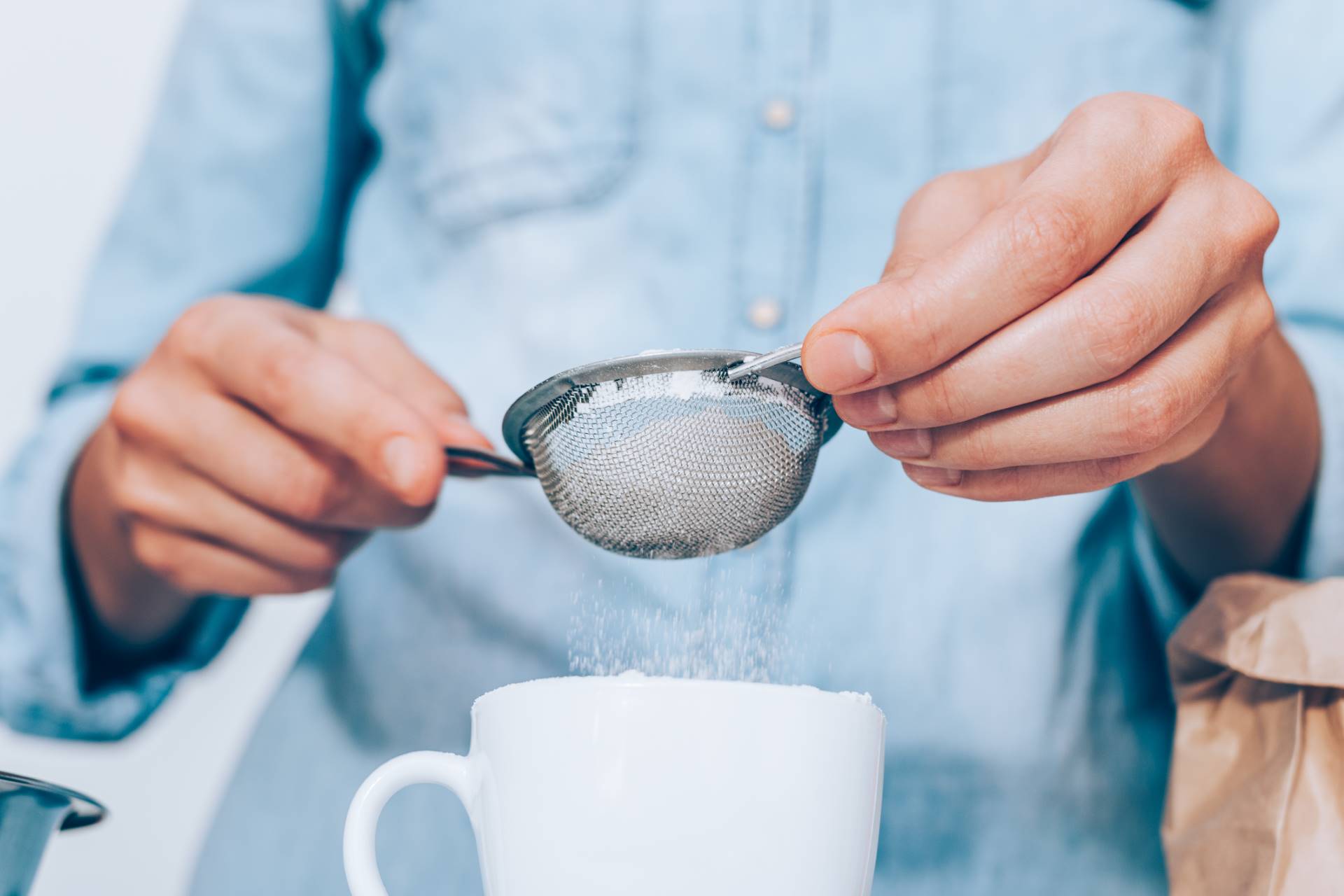 close up female's hands thoroughly and accurately sifts flour